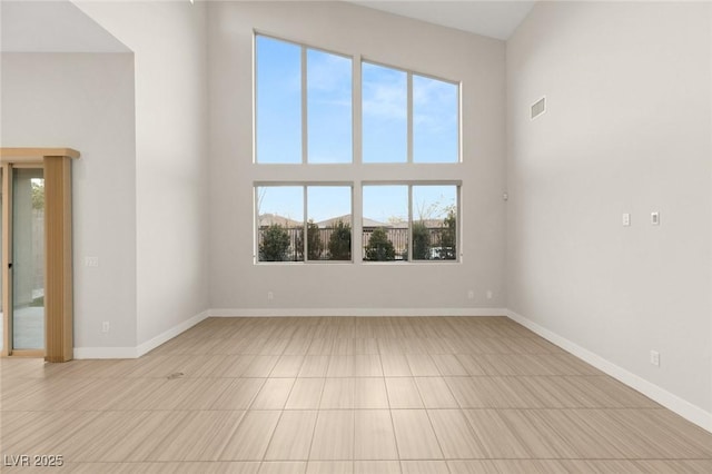 spare room with a towering ceiling and a wealth of natural light