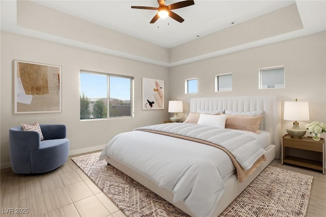 bedroom with multiple windows, a tray ceiling, and ceiling fan