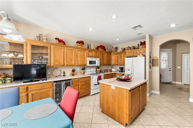 kitchen featuring beverage cooler, a center island, light tile patterned floors, white appliances, and a textured ceiling