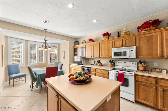 kitchen with light tile patterned floors, white appliances, a kitchen island, decorative light fixtures, and beverage cooler