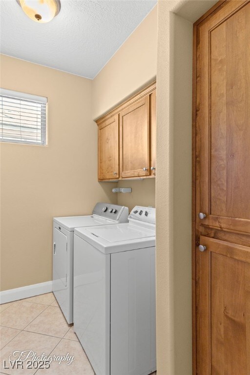 526 Highland View Ct, Mesquite, NV 89027 - washroom with washer and clothes dryer, cabinet space, light tile patterned flooring, baseboards, and a textured ceiling