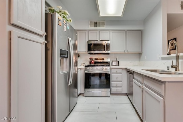 kitchen featuring sink, gray cabinets, light tile patterned flooring, and appliances with stainless steel finishes