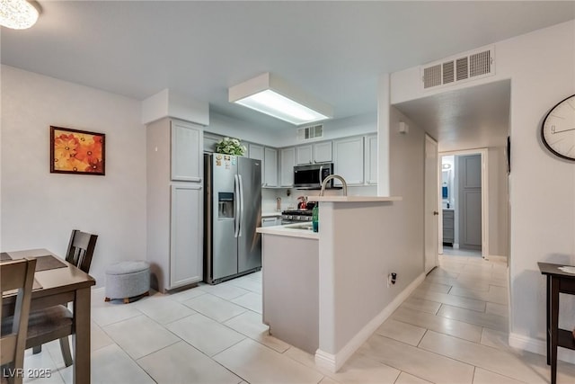 kitchen featuring stainless steel appliances, gray cabinets, light tile patterned floors, and kitchen peninsula