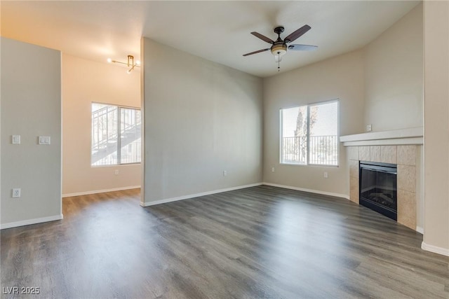 unfurnished living room featuring plenty of natural light, dark hardwood / wood-style flooring, and a tiled fireplace