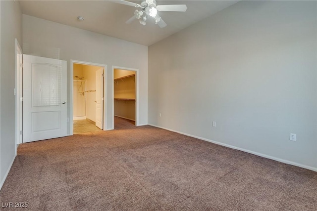 unfurnished bedroom featuring a walk in closet, light carpet, ceiling fan, and a closet