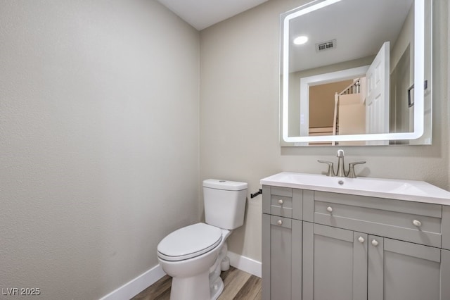 bathroom with hardwood / wood-style flooring, vanity, and toilet