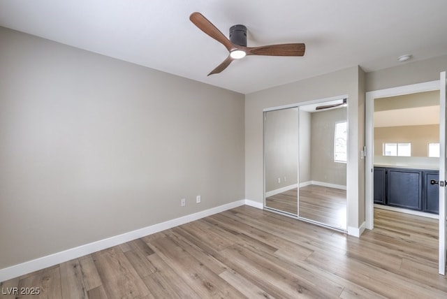 unfurnished bedroom with ceiling fan, a closet, and light wood-type flooring