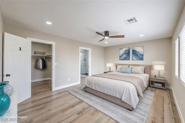 bedroom featuring connected bathroom, a closet, a walk in closet, ceiling fan, and light hardwood / wood-style flooring