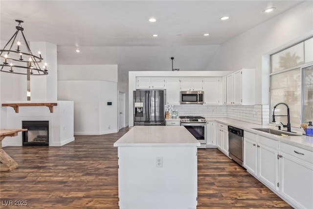 kitchen featuring pendant lighting, sink, white cabinetry, stainless steel appliances, and a center island