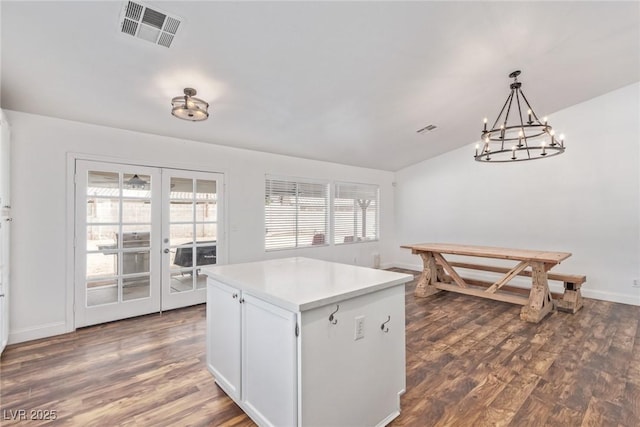 kitchen featuring french doors, vaulted ceiling, hanging light fixtures, dark hardwood / wood-style floors, and white cabinets