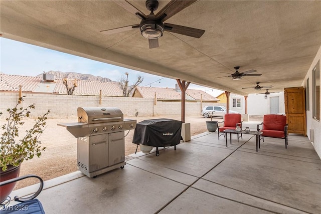 view of patio / terrace with ceiling fan, a grill, and a mountain view