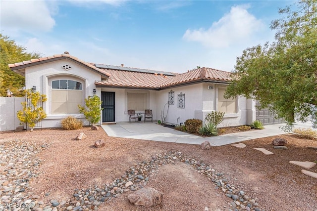 view of front of property with a patio and solar panels