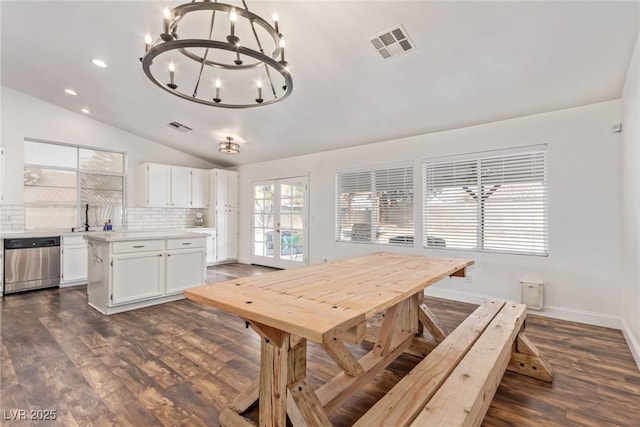 dining area with lofted ceiling, sink, a notable chandelier, dark wood-type flooring, and french doors