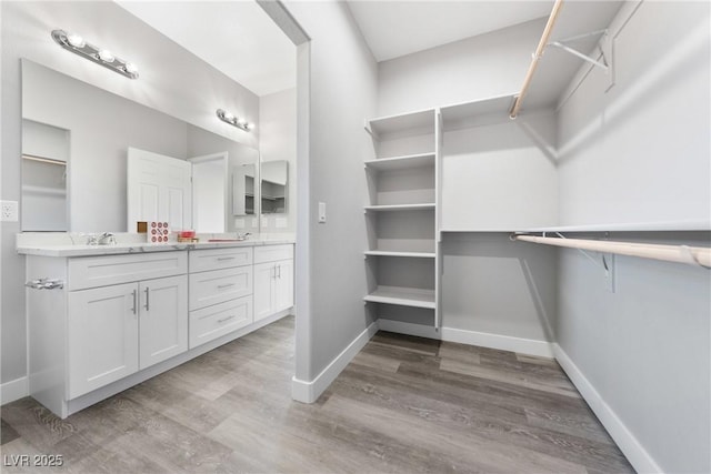 walk in closet with sink and light wood-type flooring