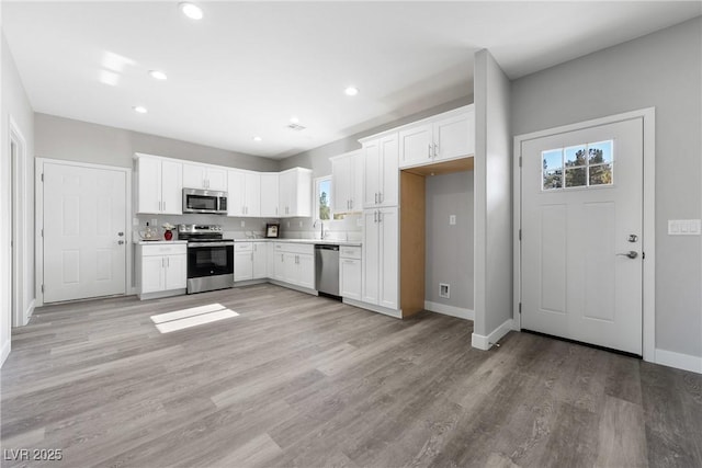 kitchen featuring stainless steel appliances, white cabinetry, and light hardwood / wood-style flooring