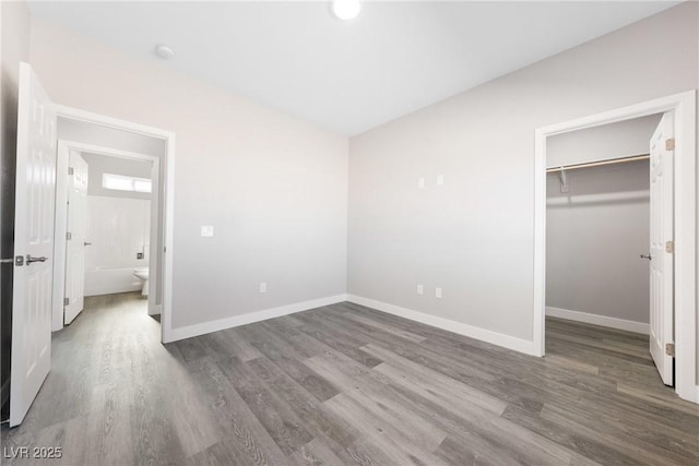 unfurnished bedroom featuring wood-type flooring, a spacious closet, and a closet