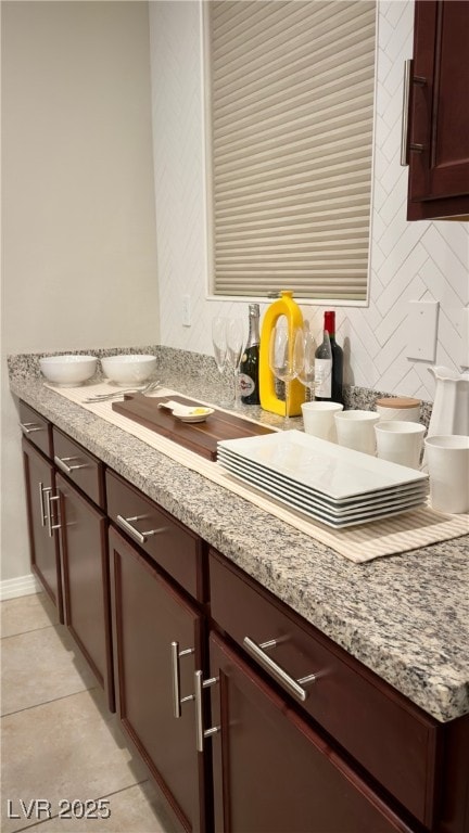 kitchen featuring light tile patterned flooring, light stone countertops, and backsplash