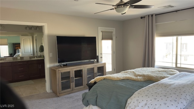 bedroom with connected bathroom, light tile patterned floors, and ceiling fan