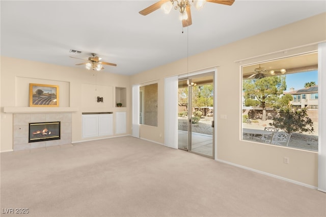 unfurnished living room with ceiling fan, light carpet, a fireplace, and built in shelves