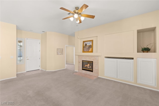 unfurnished living room featuring light carpet, a tile fireplace, and ceiling fan