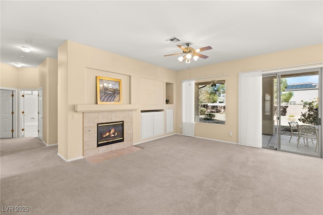 unfurnished living room with a tiled fireplace, light colored carpet, and ceiling fan