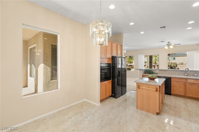 kitchen with sink, decorative light fixtures, a kitchen island, ceiling fan with notable chandelier, and black appliances