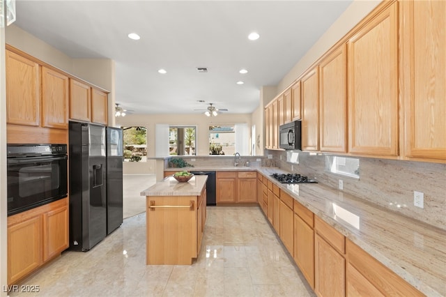 kitchen with black appliances, sink, a center island, kitchen peninsula, and light stone countertops