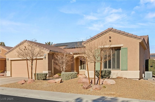 view of front of home with a garage, ac unit, and solar panels