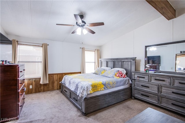 bedroom with multiple windows, light carpet, ceiling fan, and wood walls