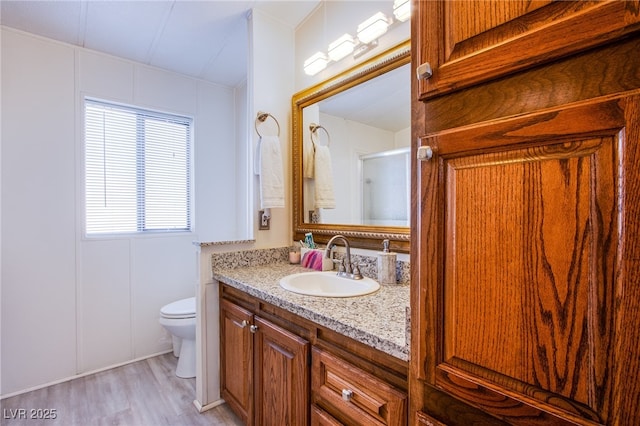 bathroom featuring hardwood / wood-style flooring, vanity, walk in shower, and toilet