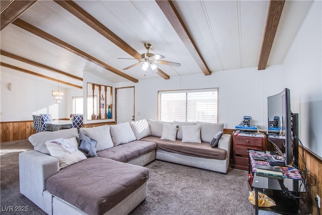 living room featuring carpet floors, ceiling fan with notable chandelier, wooden walls, and lofted ceiling with beams