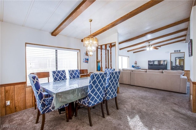 dining room with lofted ceiling with beams, carpet flooring, ceiling fan with notable chandelier, and wood walls