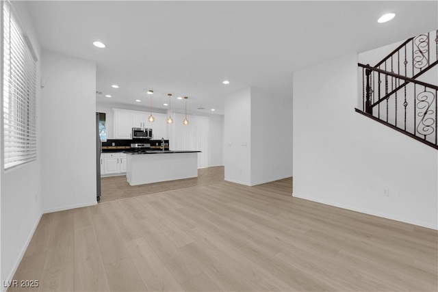 2033 Old Field Ave, North Las Vegas, NV 89081 - unfurnished living room featuring light wood-style flooring, stairway, recessed lighting, a sink, and baseboards