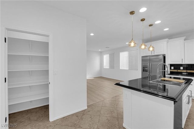 2033 Old Field Ave, North Las Vegas, NV 89081 - kitchen featuring stainless steel fridge with ice dispenser, a sink, dark countertops, white cabinetry, and an island with sink