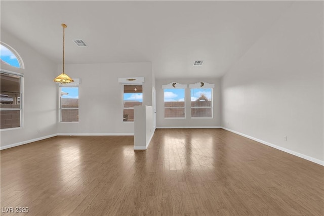 unfurnished living room featuring a healthy amount of sunlight and dark hardwood / wood-style flooring