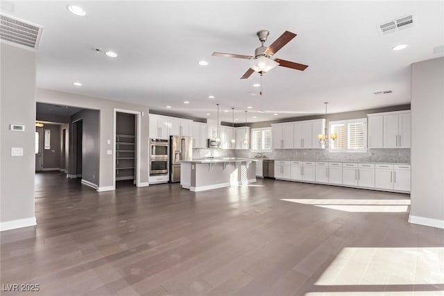 unfurnished living room with ceiling fan with notable chandelier and dark hardwood / wood-style flooring