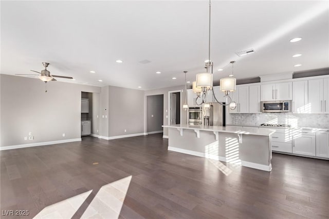 kitchen with decorative light fixtures, stainless steel appliances, a center island, and a breakfast bar