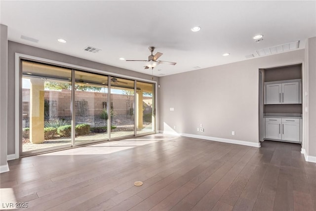 unfurnished living room featuring plenty of natural light, dark wood-type flooring, and ceiling fan