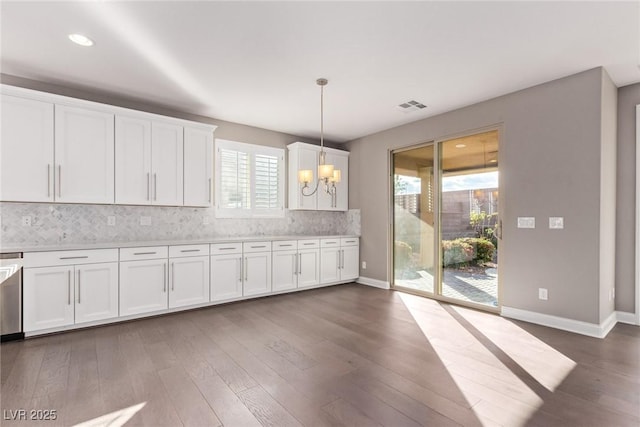 kitchen with a chandelier, hanging light fixtures, dark hardwood / wood-style flooring, decorative backsplash, and white cabinets