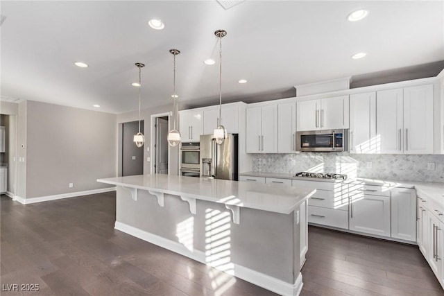 kitchen with pendant lighting, white cabinetry, stainless steel appliances, and a center island