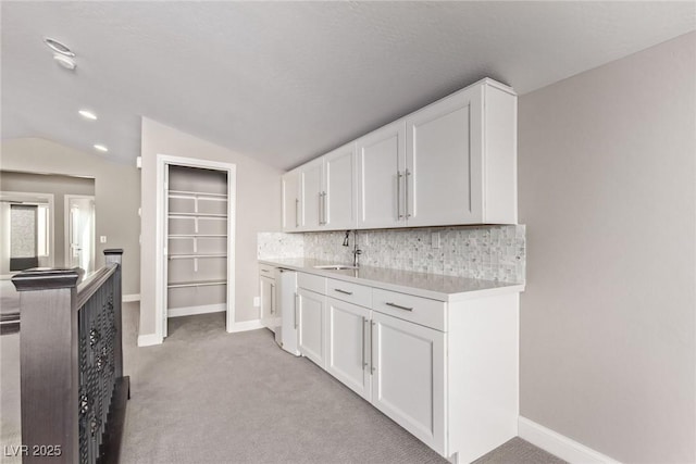 kitchen featuring lofted ceiling, sink, white cabinets, decorative backsplash, and light colored carpet