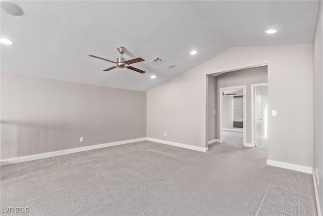 spare room with ceiling fan, light colored carpet, and vaulted ceiling