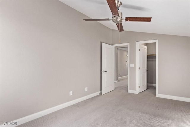 unfurnished bedroom featuring vaulted ceiling, a walk in closet, light colored carpet, ceiling fan, and a closet