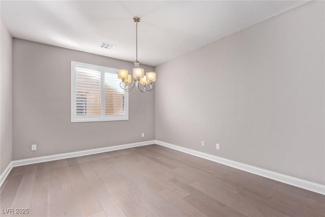 empty room with a notable chandelier and hardwood / wood-style flooring