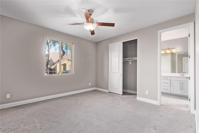 unfurnished bedroom featuring ensuite bathroom, sink, light carpet, and ceiling fan