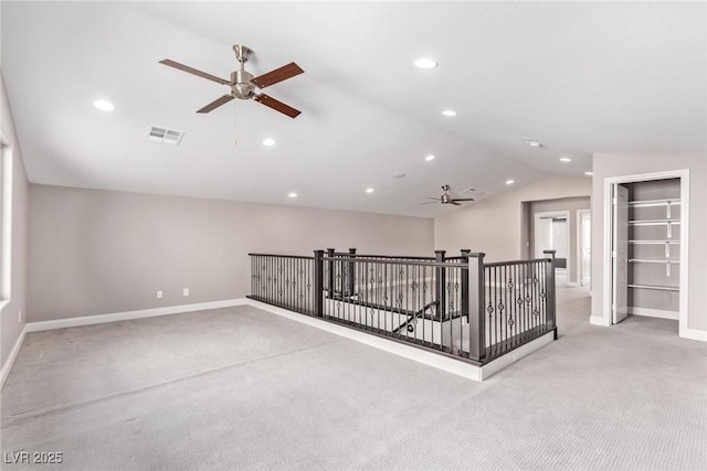 empty room featuring lofted ceiling, light colored carpet, and ceiling fan