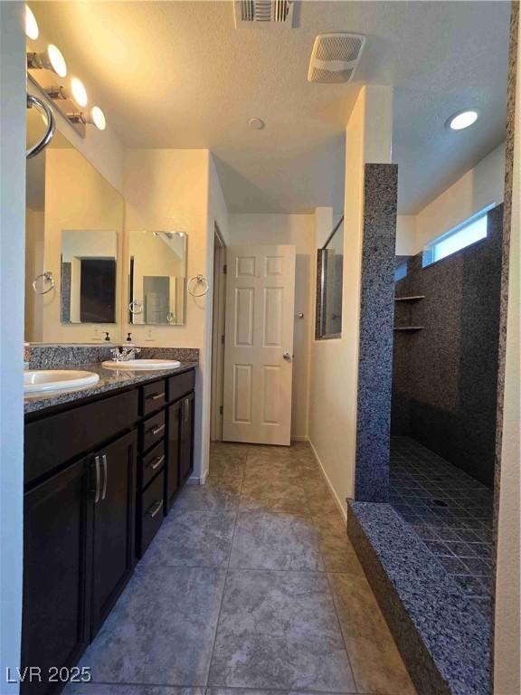 bathroom with vanity, tile patterned flooring, and a tile shower