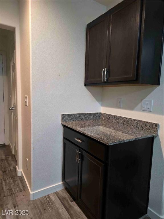 kitchen featuring dark brown cabinetry, light hardwood / wood-style flooring, and dark stone counters