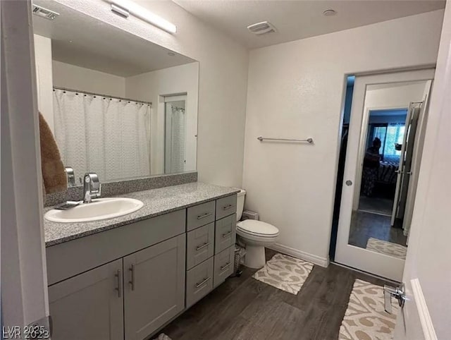 bathroom with hardwood / wood-style flooring, vanity, and toilet