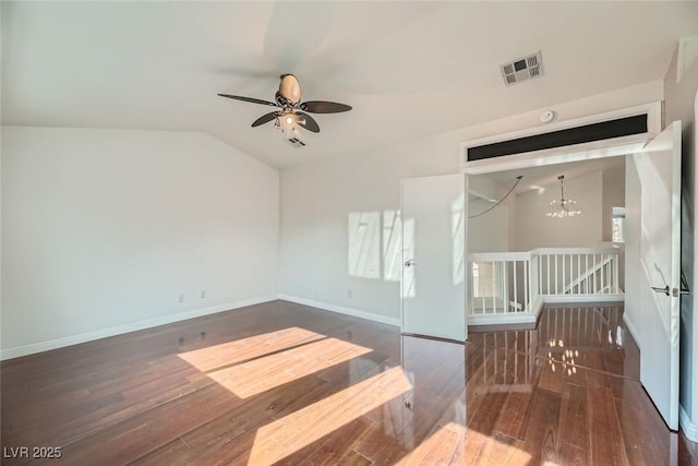 empty room featuring vaulted ceiling, dark hardwood / wood-style floors, and ceiling fan with notable chandelier